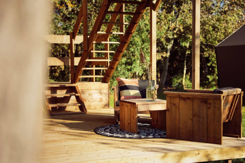 Coin salon extérieur en bois avec escalier, tapis et fauteuils à la tente safari Arriba, Resort de Parel, Pays-Bas.