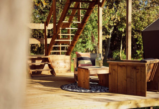 Coin salon extérieur en bois avec escalier, tapis et fauteuils à la tente safari Arriba, Resort de Parel, Pays-Bas.