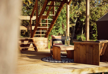 Outdoor wooden seating area with stairs and round rug at Glamping tent Arriba, Resort de Parel, Netherlands.