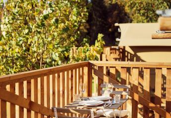 Tavolo da pranzo all’aperto su terrazza in legno vicino a tenda safari al Resort de Parel, Olanda.