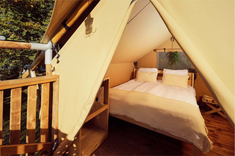 Vista interior de una elegante tienda de glamping con cama doble en el Resort de Parel en los Países Bajos.