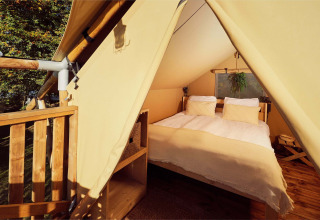 Vista interna di una tenda safari glamping con letto matrimoniale al Resort de Parel nei Paesi Bassi.