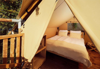 Vista interna di una tenda safari glamping con letto matrimoniale al Resort de Parel nei Paesi Bassi.