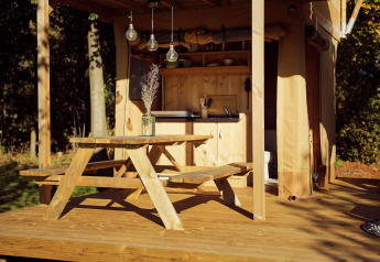Tavolo da picnic in legno davanti a una tenda safari glamping con cucina al Resort de Parel, Paesi Bassi.