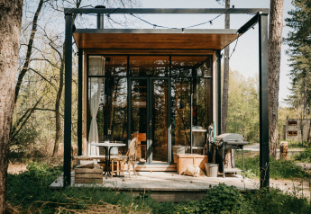 Sweet Cabin en Cosy Cabins, bosque de Limburg, Bélgica, con fachada de cristal y porche acogedor.