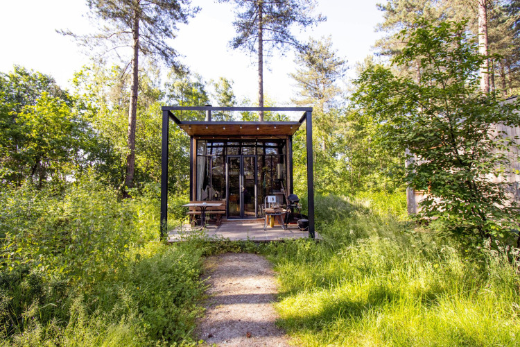 Kleine Sweet Cabin bei Cosy Cabins im Wald von Limburg, Belgien, mit moderner Glasfront und Terrasse.