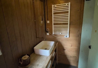 Accogliente bagno in legno con lavabo, scaldasalviette e luci a soffitto in una sistemazione glamping.