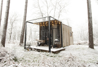Sweet Cabin a Cosy Cabins nella foresta di Limburgo, Belgio, coperta di neve e luci calde sulla veranda.
