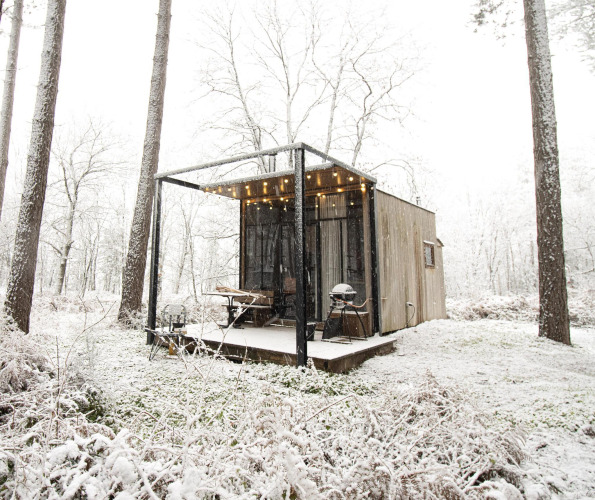 Gemütliche Sweet Cabin im Wald von Limburg, Belgien, im Schnee mit Lichtern auf der Veranda.