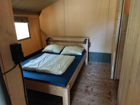 Interno di una tenda safari con servizi igienici presso Camping de Beukenhof, Paesi Bassi, con letto.