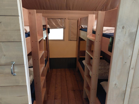 Binnenzicht van een safaritent met stapelbedden en houten vloer bij Camping de Beukenhof, Nederland.