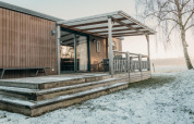 Cabaña de madera con terraza cubierta y nieve en Family Lodge, Holiday park De Boshoek, Países Bajos.