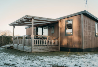 Family Lodge en Holiday park De Boshoek, Países Bajos, cabaña de madera moderna con porche y césped nevado