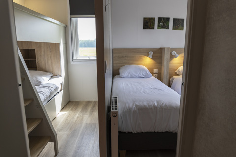 Habitación de lodge moderna con dos camas individuales, literas y una ventana con luz natural.