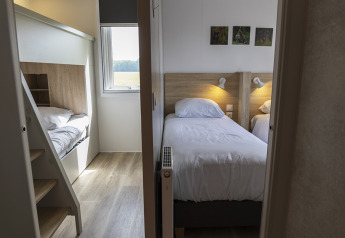 Moderne lodgekamer met twee eenpersoonsbedden, stapelbedden en een raam met uitzicht naar buiten.