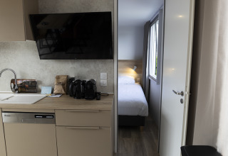 Cocina moderna de lodge con fregadero, lavavajillas, TV y vista a una habitación con cama individual.