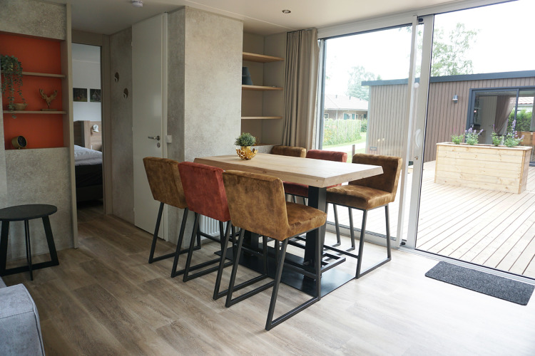 Comedor con seis sillas y mesa grande en Family lodge en Holiday park De Boshoek, Países Bajos, con terraza.