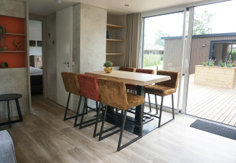 Dining area with six chairs and a large table in Family lodge at Holiday park De Boshoek, Netherlands.