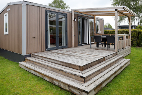 Außenaufnahme der Family Lodge im Holiday Park De Boshoek, Niederlande, mit Holzterrasse.