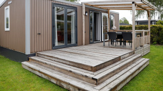 Außenaufnahme der Family Lodge im Holiday Park De Boshoek, Niederlande, mit Holzterrasse.