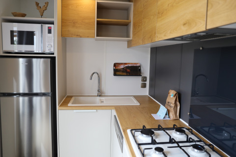 Moderne kitchenette bij Family Lodge op Holiday park De Boshoek in Nederland met koelkast en gasfornuis.