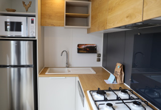 Pequeña cocina moderna en Family Lodge, Holiday park De Boshoek, Países Bajos, con microondas y fregadero.