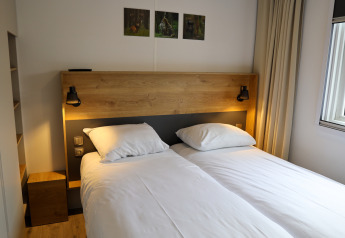Familienzimmer mit zwei Einzelbetten in der Family Lodge im Ferienpark De Boshoek, Niederlande, modern eingerichtet.