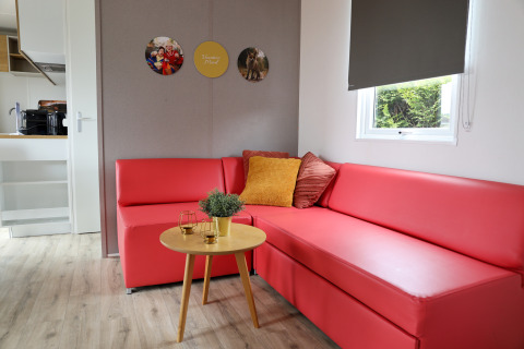 Wohnzimmer der Family Lodge im Holiday Park De Boshoek, mit rotem Sofa und Holztisch, Niederlande.