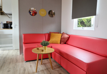 Stue i Family Lodge på Holiday park De Boshoek, med rød sofa, rundt bord og puder, Holland.