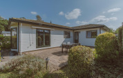 Foto exterior del chalet Wilbrink en Holiday park De Boshoek, Países Bajos, con terraza, mesa y vegetación.