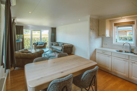 Sala de estar y cocina en el Wilbrink chalet del Holiday park De Boshoek, Países Bajos, con sofás y mucha luz natural.