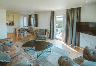 Sala de estar con sofás y mesa en Wilbrink chalet, Holiday park De Boshoek, Países Bajos, decoración luminosa.