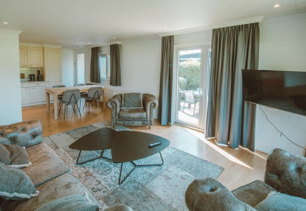 Living room with sofas and dining table in Wilbrink chalet at Holiday park De Boshoek, Netherlands, bright decor.