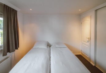Bright bedroom with two single beds in the Wilbrink chalet at Holiday park De Boshoek, Netherlands.