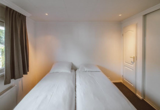 Bright bedroom with two single beds in the Wilbrink chalet at Holiday park De Boshoek, Netherlands.