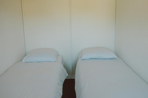 Dos camas individuales con sábanas y almohadas blancas en el Wilbrink chalet de Holiday park De Boshoek.