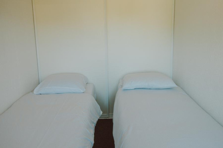 Dos camas individuales con sábanas y almohadas blancas en el Wilbrink chalet de Holiday park De Boshoek.