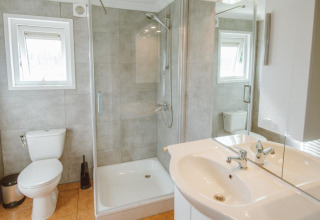 Modern bathroom with shower, toilet, and sink in Wilbrink chalet at Holiday park De Boshoek, the Netherlands.