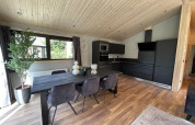 Cocina y comedor modernos en una cabaña de madera con muebles oscuros en Hackfort Wood 6, De Utrechtse Heuvelrug.