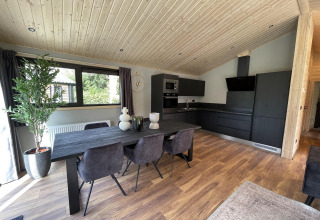 Cucina e sala da pranzo moderne in legno con arredi scuri nel lodge Hackfort Wood 6, De Utrechtse Heuvelrug.