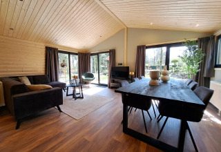 Zona giorno e pranzo moderna nel lodge Hackfort Wood 6 a De Utrechtse Heuvelrug, Paesi Bassi, con grandi finestre.
