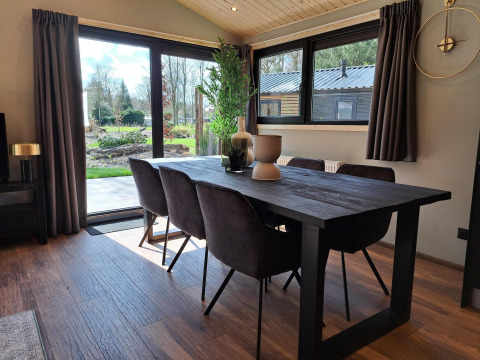 Moderne eethoek met donkere tafel en stoelen, grote ramen met tuinzicht bij Hackfort Wood 6 in Nederland.