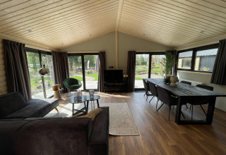 Interno di un lodge moderno con pavimento in legno, soffitto alto e ampie finestre a De Utrechtse Heuvelrug.