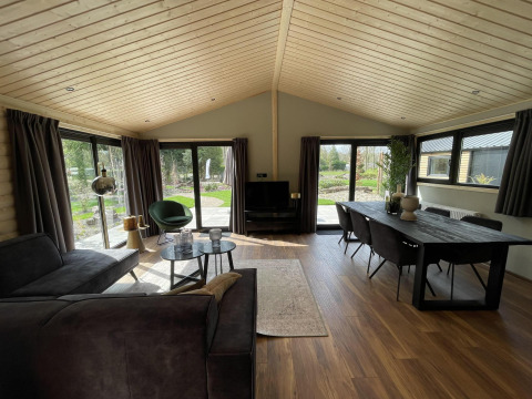Intérieur de lodge moderne avec parquet, plafond en bois et grandes fenêtres à De Utrechtse Heuvelrug.