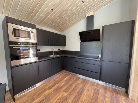 Cocina moderna en Hackfort Wood 6, De Utrechtse Heuvelrug, Países Bajos, con armarios oscuros.