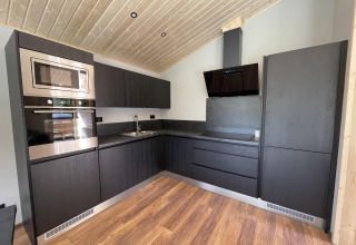 Cocina moderna en Hackfort Wood 6, De Utrechtse Heuvelrug, Países Bajos, con armarios oscuros.