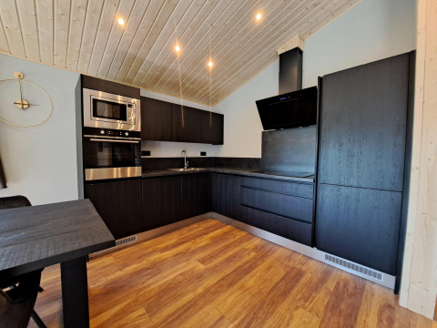 Moderne zwarte keuken met houten plafond en vloer in Hackfort Wood 6, De Utrechtse Heuvelrug, Nederland.