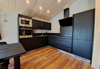 Cucina moderna nera con soffitto e pavimento in legno a Hackfort Wood 6, De Utrechtse Heuvelrug, Paesi Bassi.