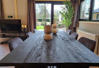 Spisestue i Hackfort Wood 6-lodge ved De Utrechtse Heuvelrug, Holland, med udsigt til have gennem store vinduer.