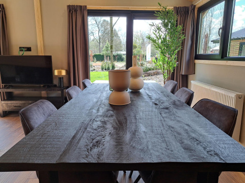 Comedor de la cabaña Hackfort Wood 6 en De Utrechtse Heuvelrug, Países Bajos, con ventanales al jardín.